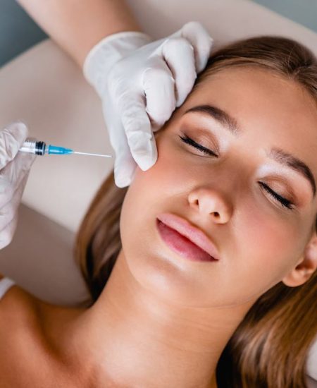 Young woman gets beauty facial injections in salon